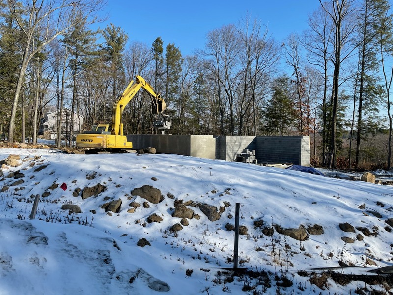Excavator working a snow-covered commercial building site