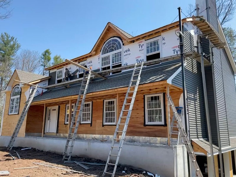 New timber-framed house under construction with ladders against the facade